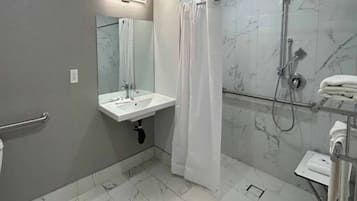 A bathroom with a white sink, a mirror, a shower with a glass door, and a towel rack.