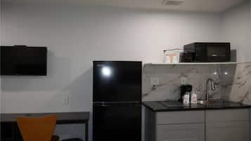 A compact kitchen with a refrigerator, microwave, and sink.