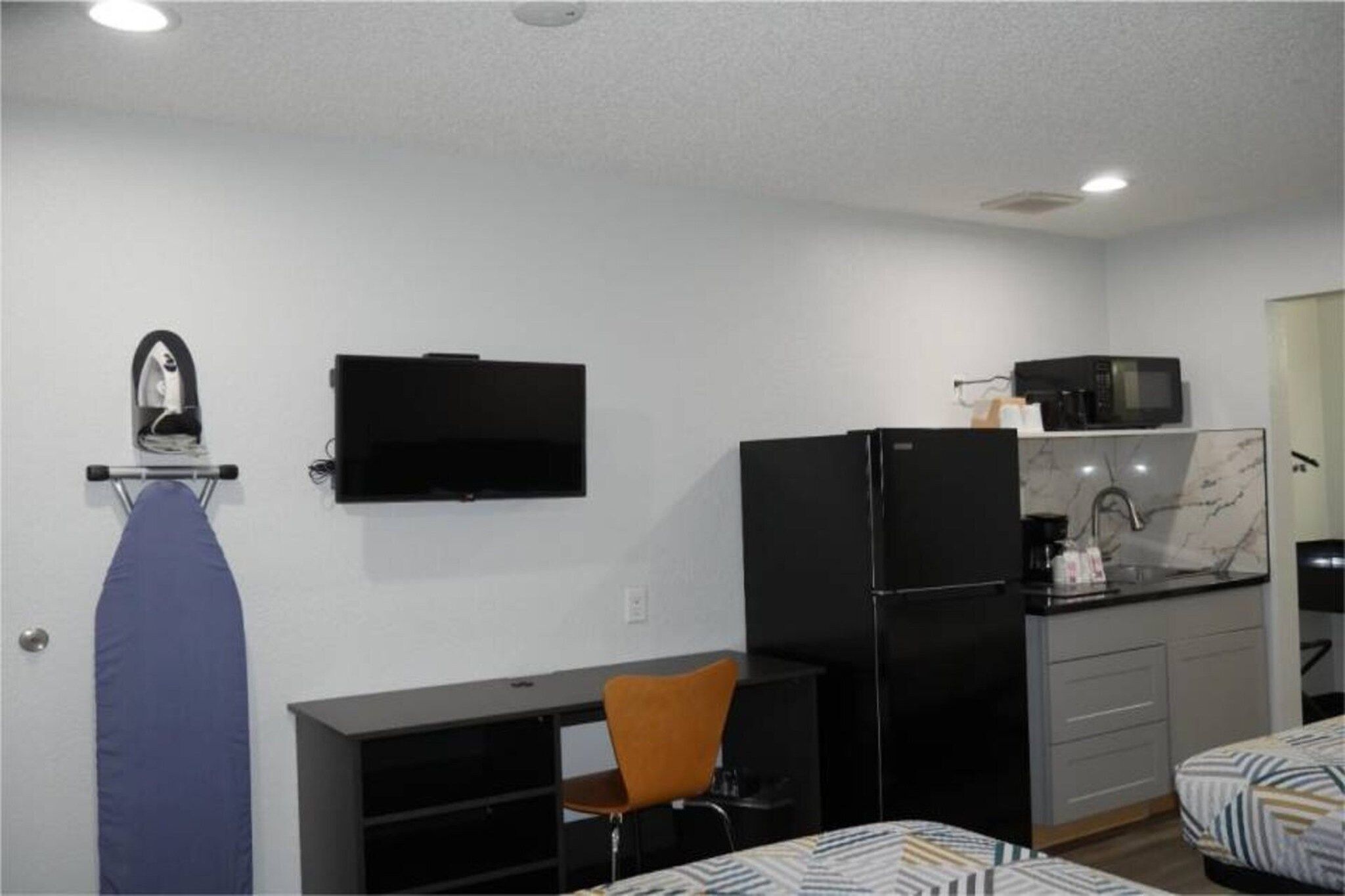 A compact room with a bed, a desk, a chair, a television, a refrigerator, and a microwave.