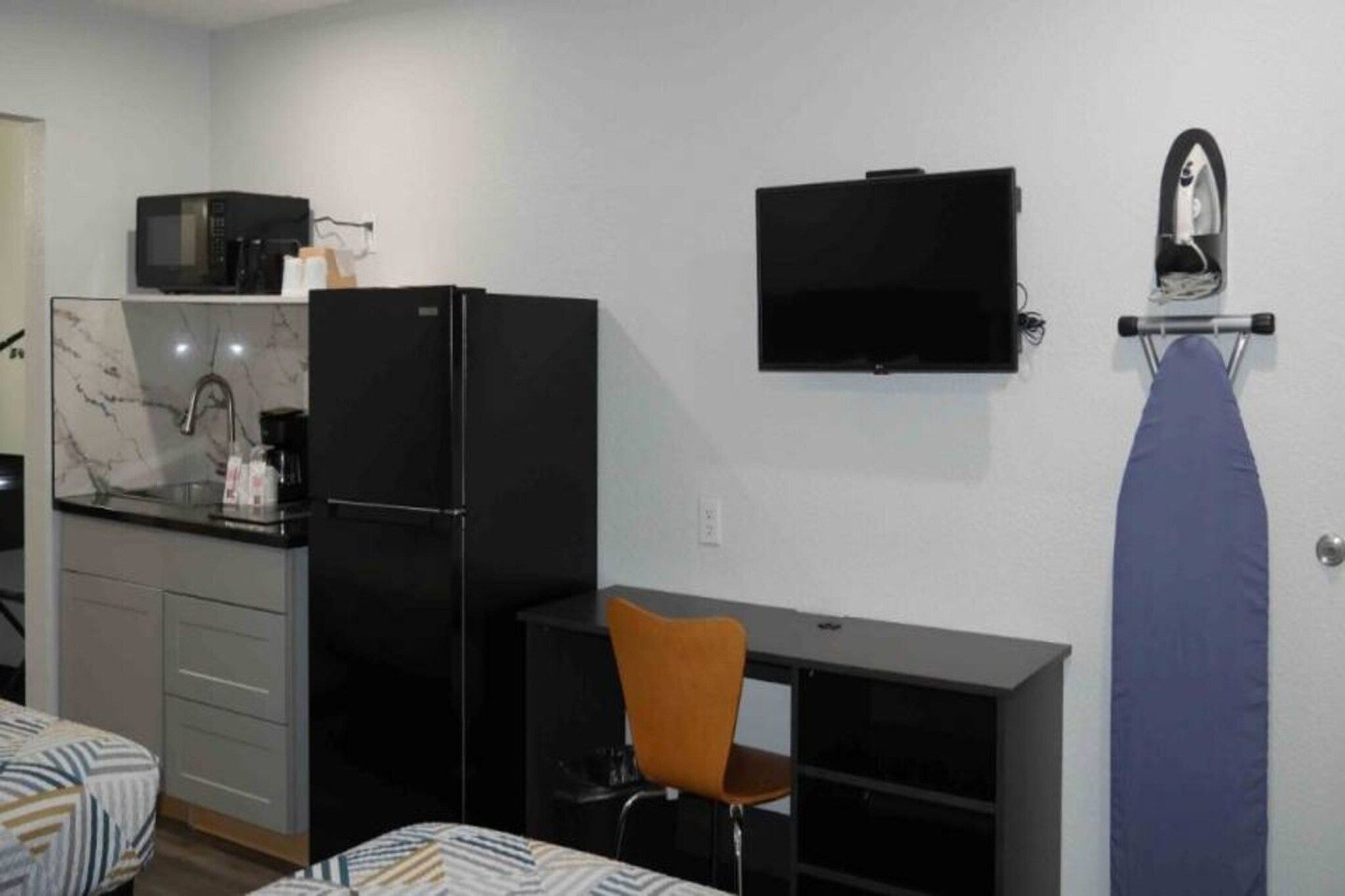 A compact room with a kitchenette, a bed, a desk, and a chair.