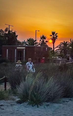 Ein Sonnenuntergang mit Palmen und einem Gebäude im Hintergrund.