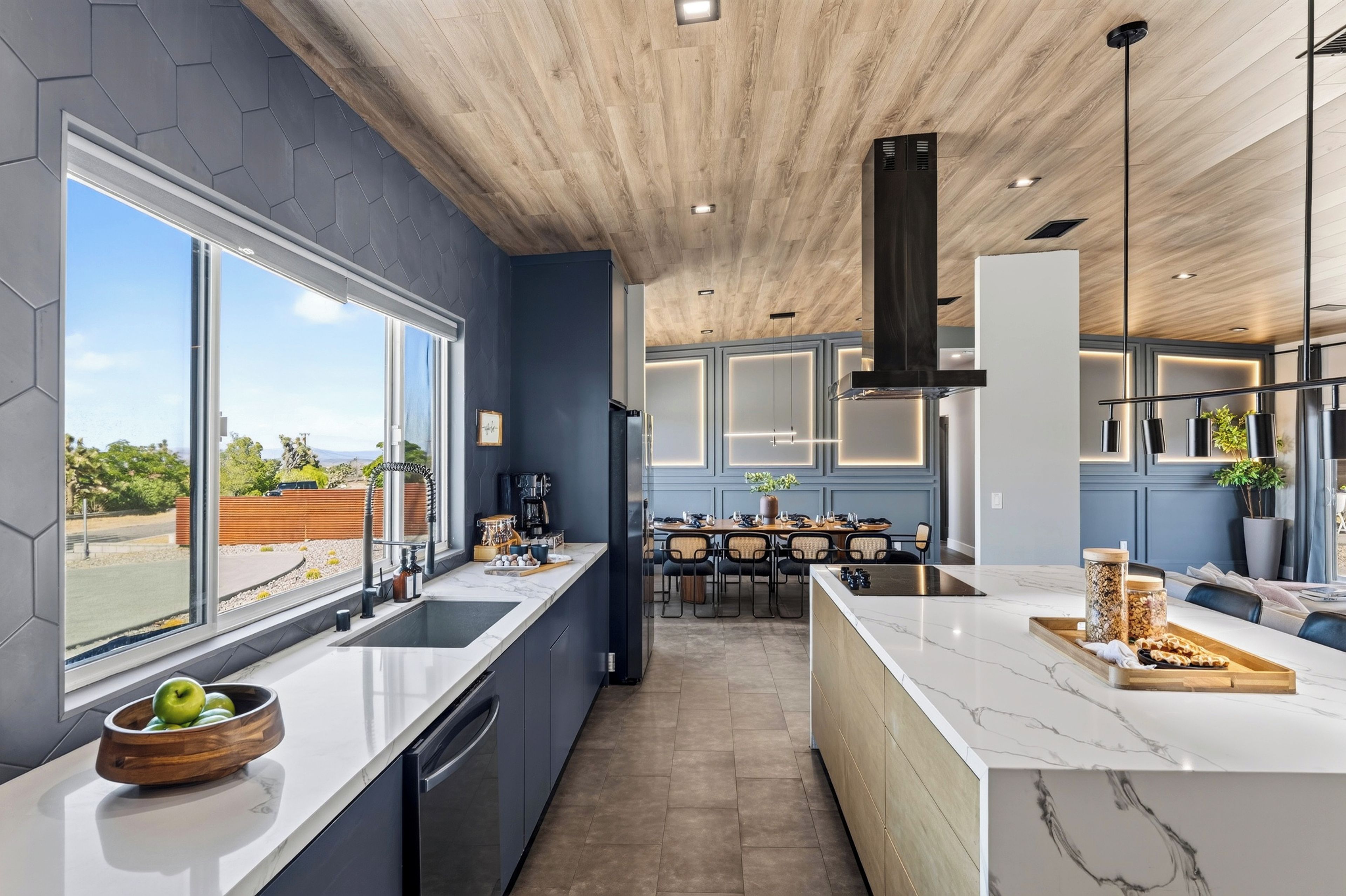 A modern kitchen with a large island, built-in appliances, and a view of the outdoors.