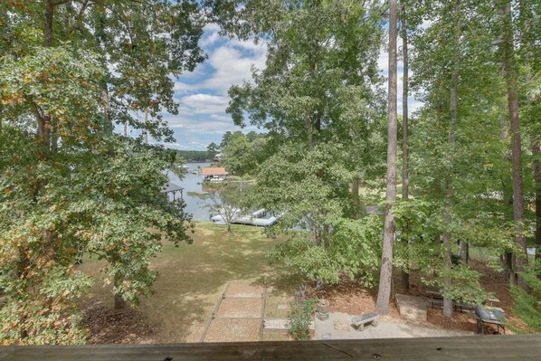 A view of a lakeside property with a deck, a barbecue area, and a gazebo.