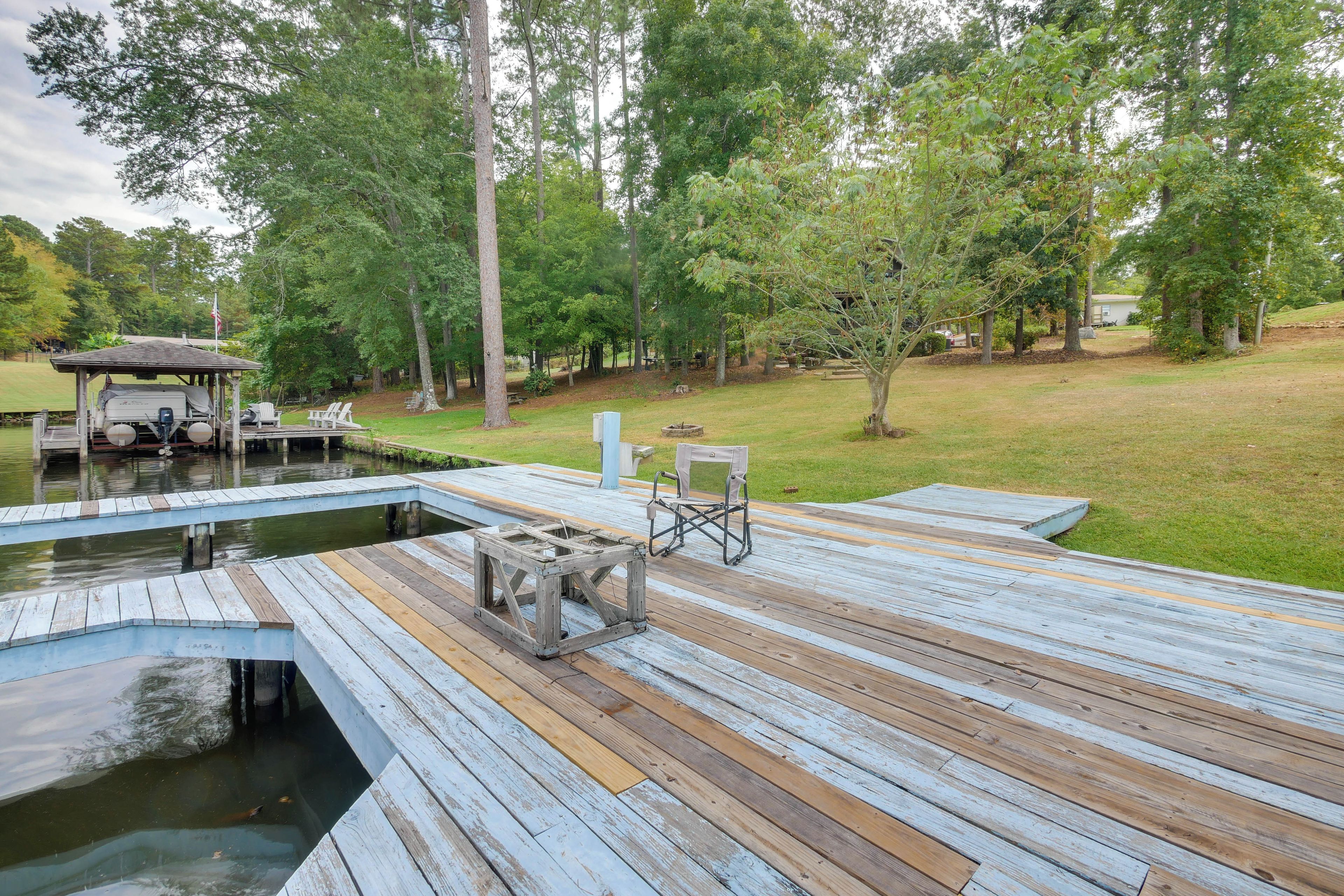 A wooden dock extending into a body of water, with a covered seating area and a small table.