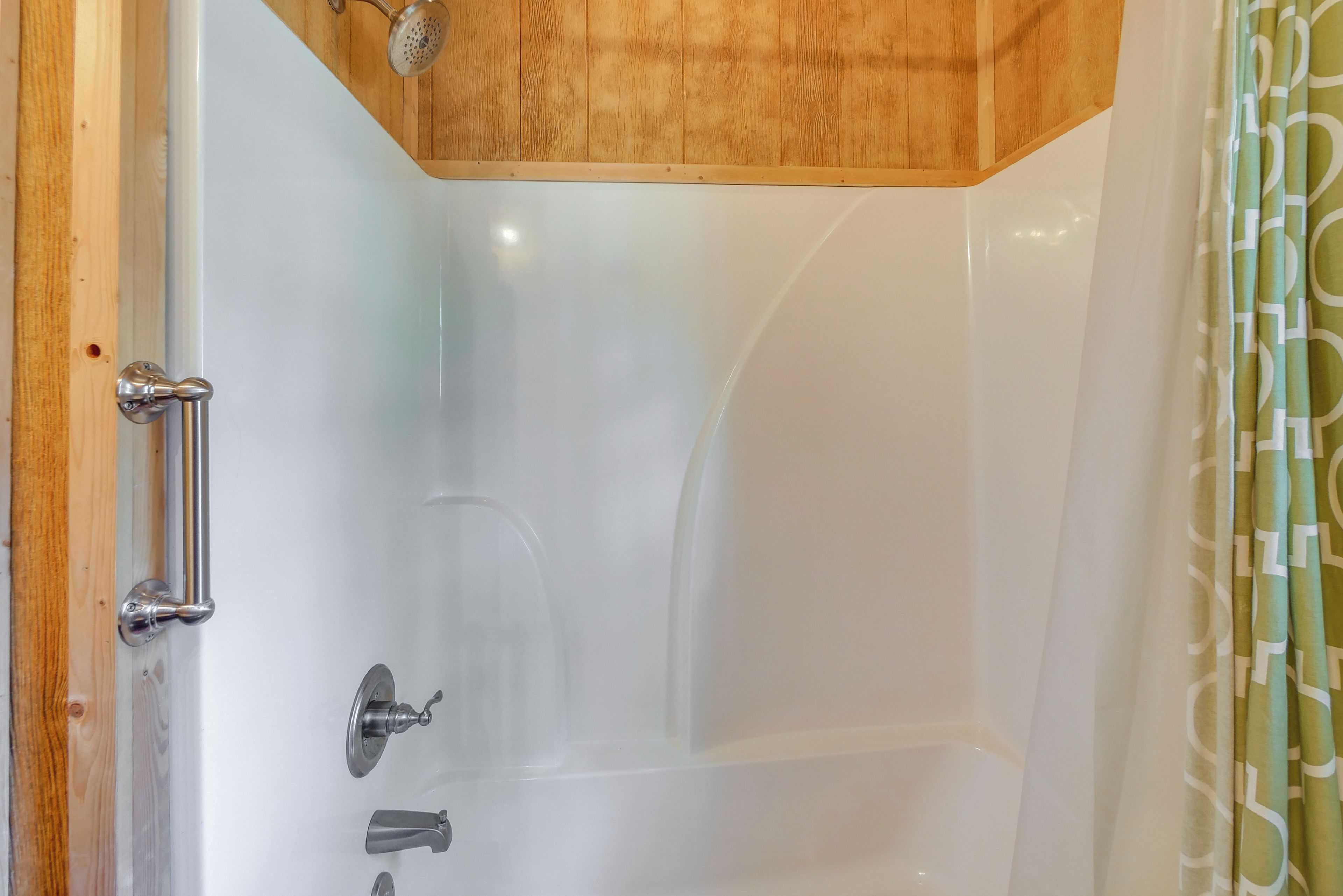 A bathroom with a bathtub, a shower, and a wooden ceiling.