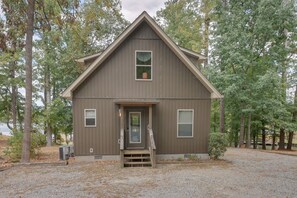 Une cabane à deux étages avec un porche à l’avant, une petite fenêtre et une porte.