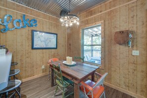 A wooden interior with a dining table, chairs, a map, and a window.