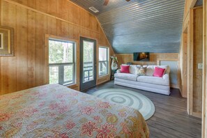 A cozy bedroom with a large bed, a white sofa, and a ceiling fan.
