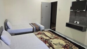 Ett hotellrum med två sängar, en takfläkt, en tv och en dörr.