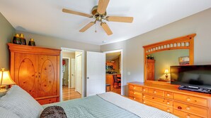A bedroom with a bed, a dresser, a television, and a ceiling fan.