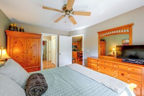 A bedroom with a bed, a dresser, a television, and a ceiling fan.