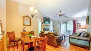 A spacious living area with a dining table, chairs, a sofa, and a ceiling fan.