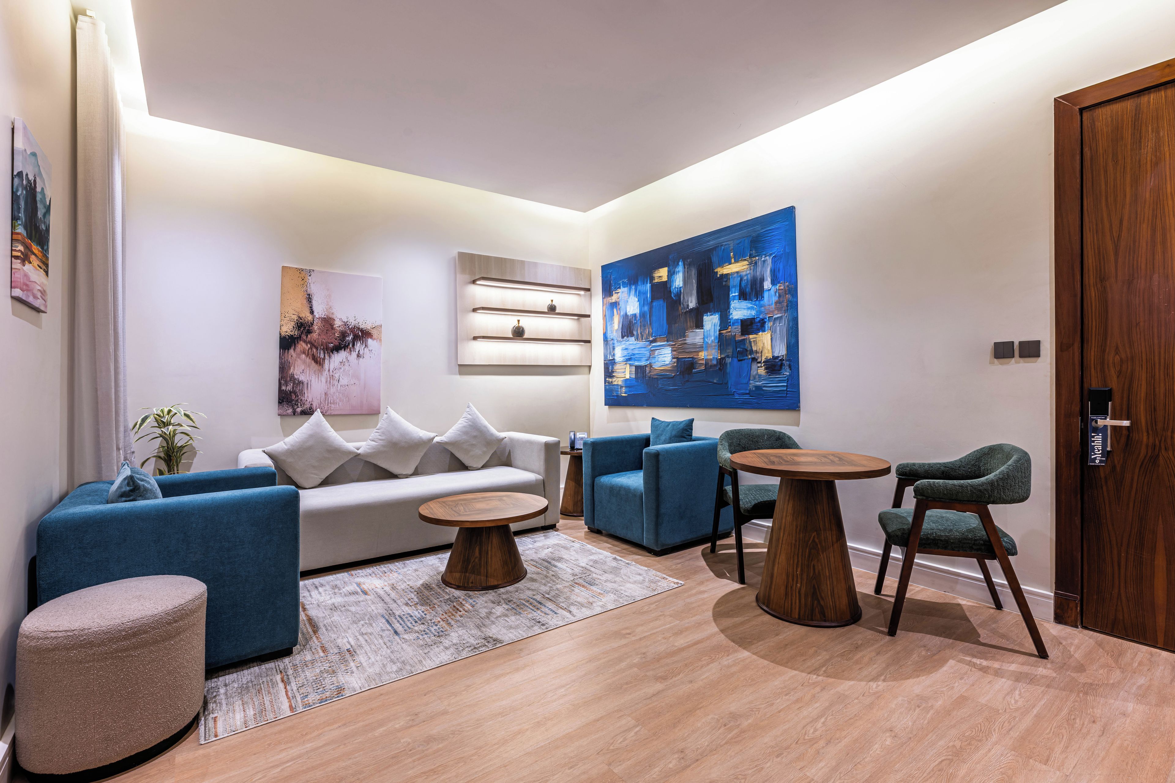 A modern living room with a sofa, armchairs, a coffee table, and a painting on the wall.