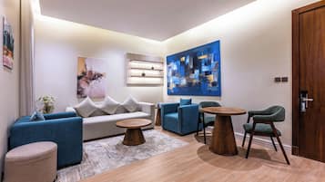 A modern living room with a sofa, armchairs, a coffee table, and a painting on the wall.