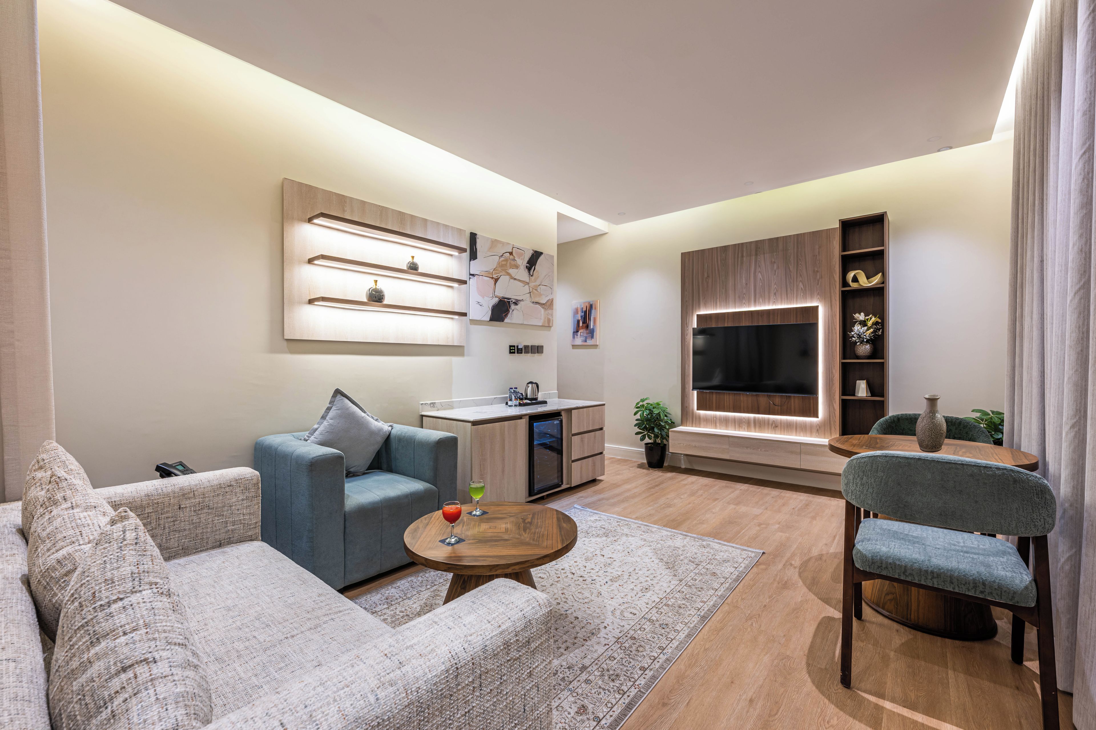 A modern living room with a sofa, a coffee table, a TV, and a kitchen area.