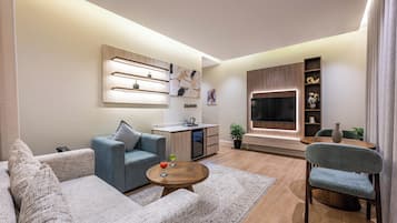 Una sala de estar moderna con un sofá, una mesa de centro, un televisor y una zona de cocina.