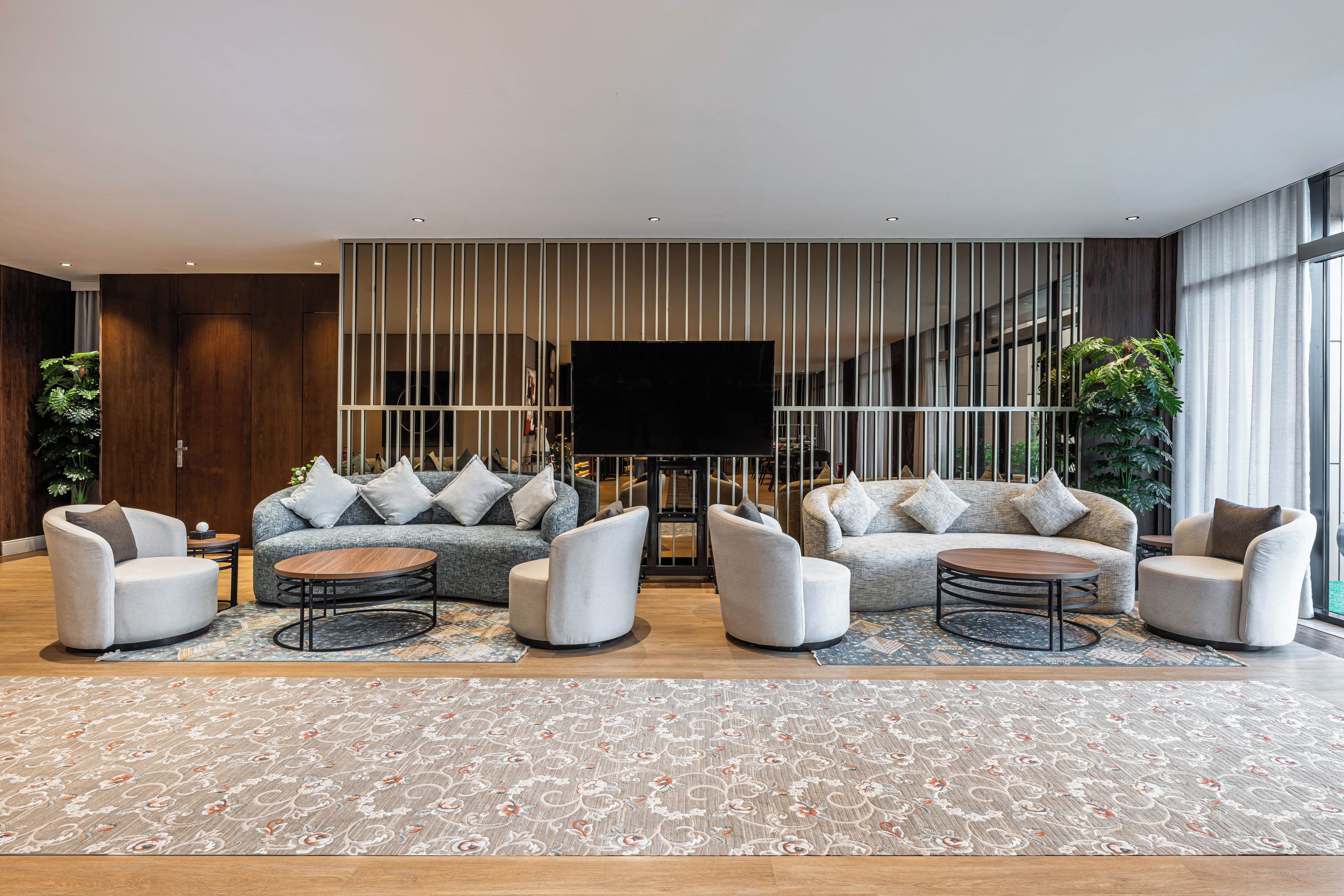 A modern living room with a sectional sofa, two armchairs, a coffee table, and a large flat-screen TV.