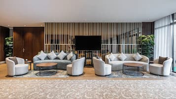 Una sala moderna con un sofá seccional, dos sillones, una mesa de centro y un televisor de pantalla plana grande.