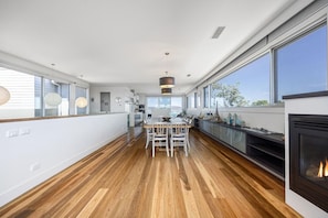 A modern kitchen with a dining area, large windows, and a fireplace. - Stanley House Mt Martha. (Mount Martha)