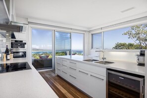 A modern kitchen with a large window, a dishwasher, and a view of the sea. - Stanley House Mt Martha. (Mount Martha)
