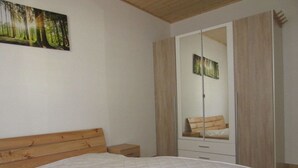 Een slaapkamer met een bed, een nachtkastje, een garderobe met spiegel en een schilderij aan de muur.
