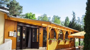 Een houten gebouw met een overdekt terras, een houten hek en een bord met een restaurant.