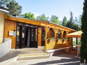 Un edificio de madera con un espacio de asientos techado al aire libre, una valla de madera y un letrero de restaurante.