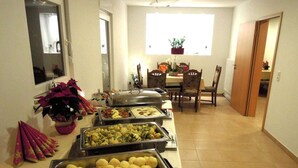 Een buffetopstelling met diverse gerechten en een eethoek met stoelen en een tafel.