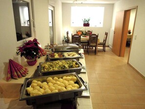 Una mesa de buffet con diversos alimentos y una zona de comedor con sillas y una mesa.