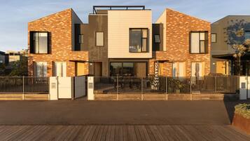 A modern two-story residential building with a brick facade, large windows, and a gated entrance.
