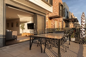 An outdoor patio with a dining table and chairs, a sofa, and a TV mounted on the wall. - Waterfront Escape Rooftop Marina Views & Parking (Port Adelaide)