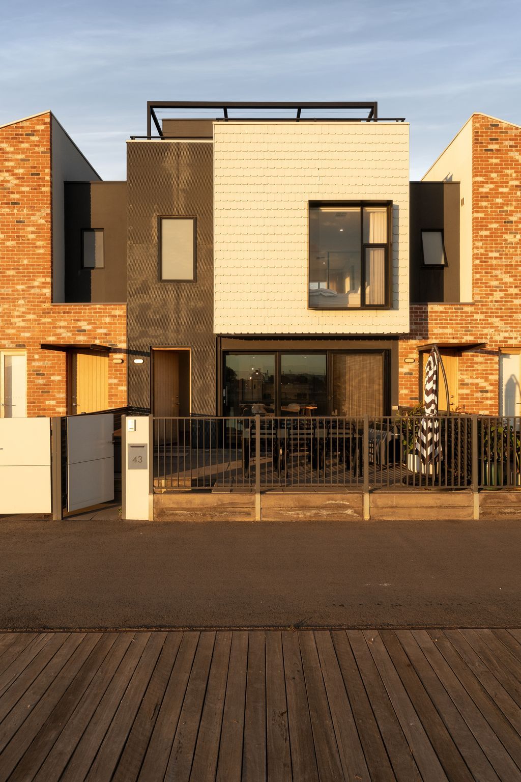A modern building with a flat roof, large windows, and a wooden deck in front.