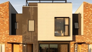 Un edificio moderno con techo plano, ventanas grandes y una terraza de madera al frente.