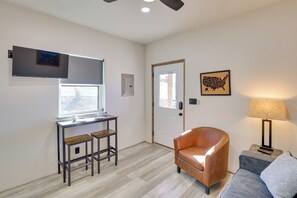A modern living room with a sofa, a coffee table, a lamp, and a TV mounted on the wall. - Trail Access & Views! 90-Acre Haven in Hot Springs (Hot Springs)