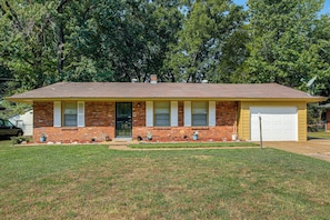 A single-story brick house with a gabled roof, a front garage, and a small front yard with a lawn and potted plants. - 4 Mi to Graceland! Cozy Home w/ Patio & Yard (Memphis)