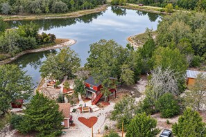 Ein Haus mit rotem Anstrich am Seeufer, mit einem herzförmigen Garten und einer Anlegestelle, die ins Wasser hineinreicht.