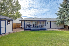 A residential house with a front porch, a fenced backyard, and a large tree. - Furnished Stay Near Peterson Space Force Base (Colorado Springs)