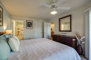 A bedroom with a bed, dresser, mirror, and ceiling fan.