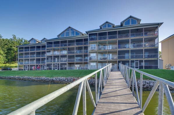 A multi-story hotel with balconies, a wooden deck, and a view of a body of water.