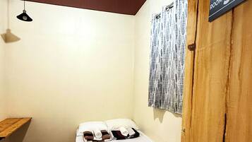 A single bed with a wooden headboard in a room with a wooden floor and a slanted ceiling. A sign indicates the room number as 302.