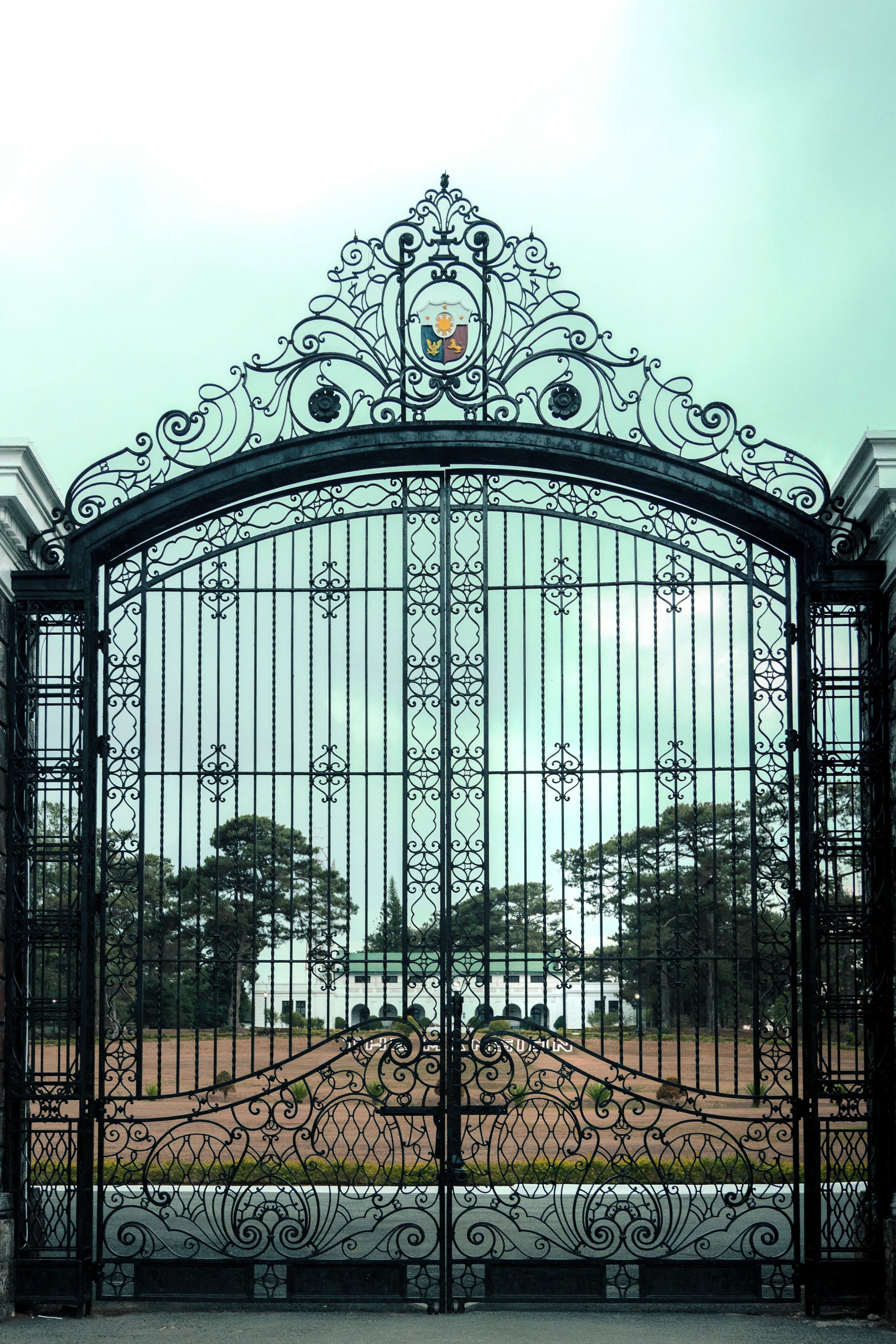 A wrought iron gate with intricate designs and a crest emblem.