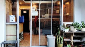 A storefront with a glass door, a 'No Pets Allowed' sign, and potted plants on the right.