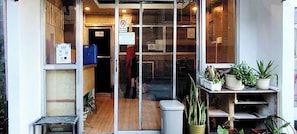 Vitrine com porta de vidro, placa indicando 'Não Aceitamos Animais de Estimação' e vasos de plantas à direita.