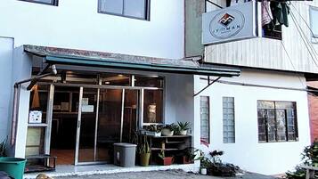 A building with a storefront, a sign above the entrance, and a small outdoor area with plants.
