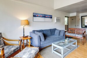 Ein Wohnzimmer mit einer Couch, einem Couchtisch, einer Lampe, einem Gemälde und einer Tür zu einem anderen Raum.