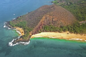 An aerial view of a coastal area with a prominent hill, a beach, and clear blue waters. - Oceanside Oasis: Pvt Balcony, Pool, Hot tub, Beach (Kihei)