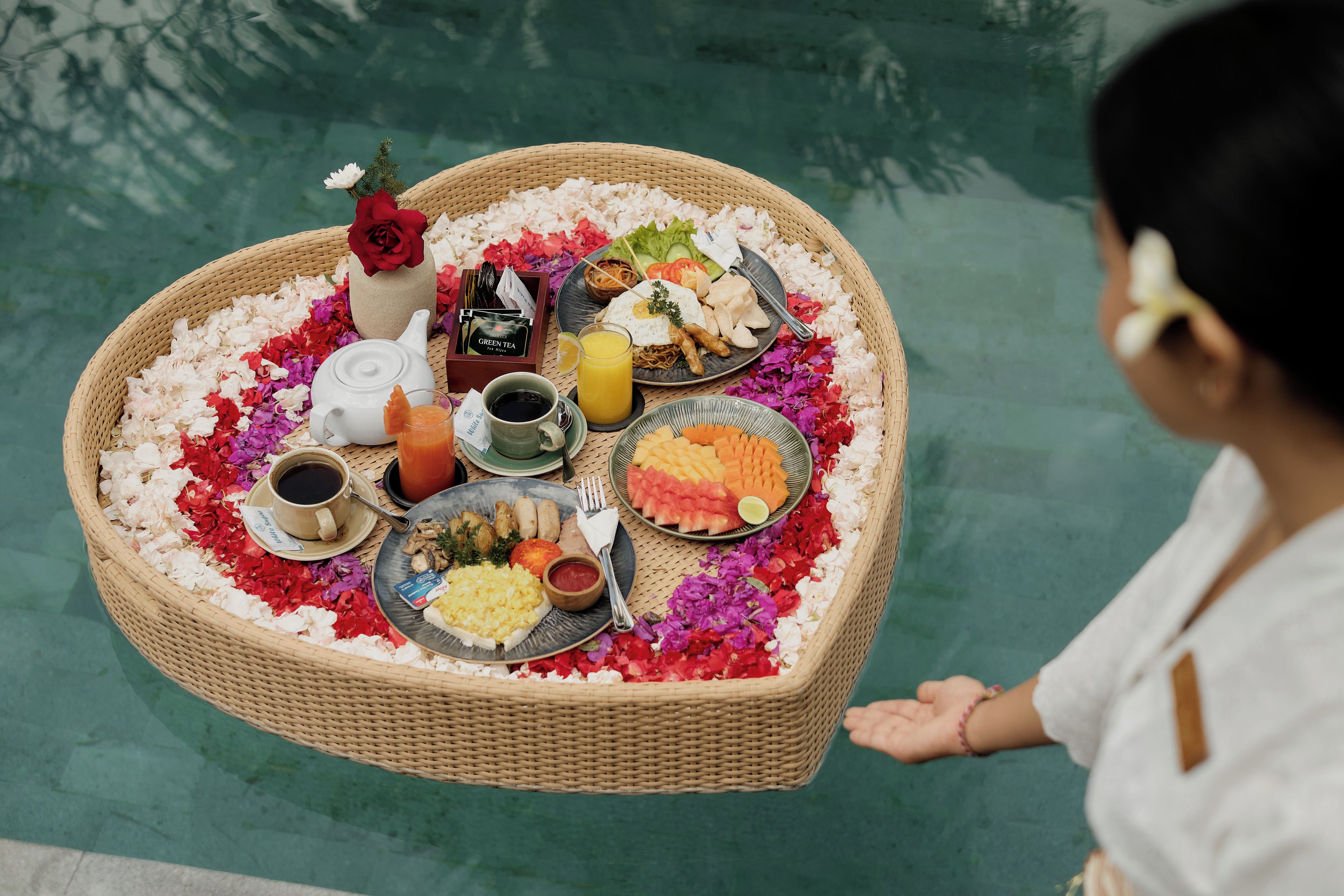 Una bandeja con forma de corazón que contiene diversas opciones de comida y bebidas, como una tetera, una taza de café y platos de comida.