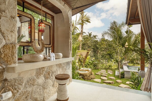 A stone wall with a shelf holding decorative items and a hanging lantern. - Dedari Sebatu Villa (Gianyar)