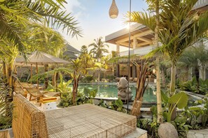A pool area with lounge chairs, a stone statue, and tropical plants. - Dedari Sebatu Villa (Gianyar)