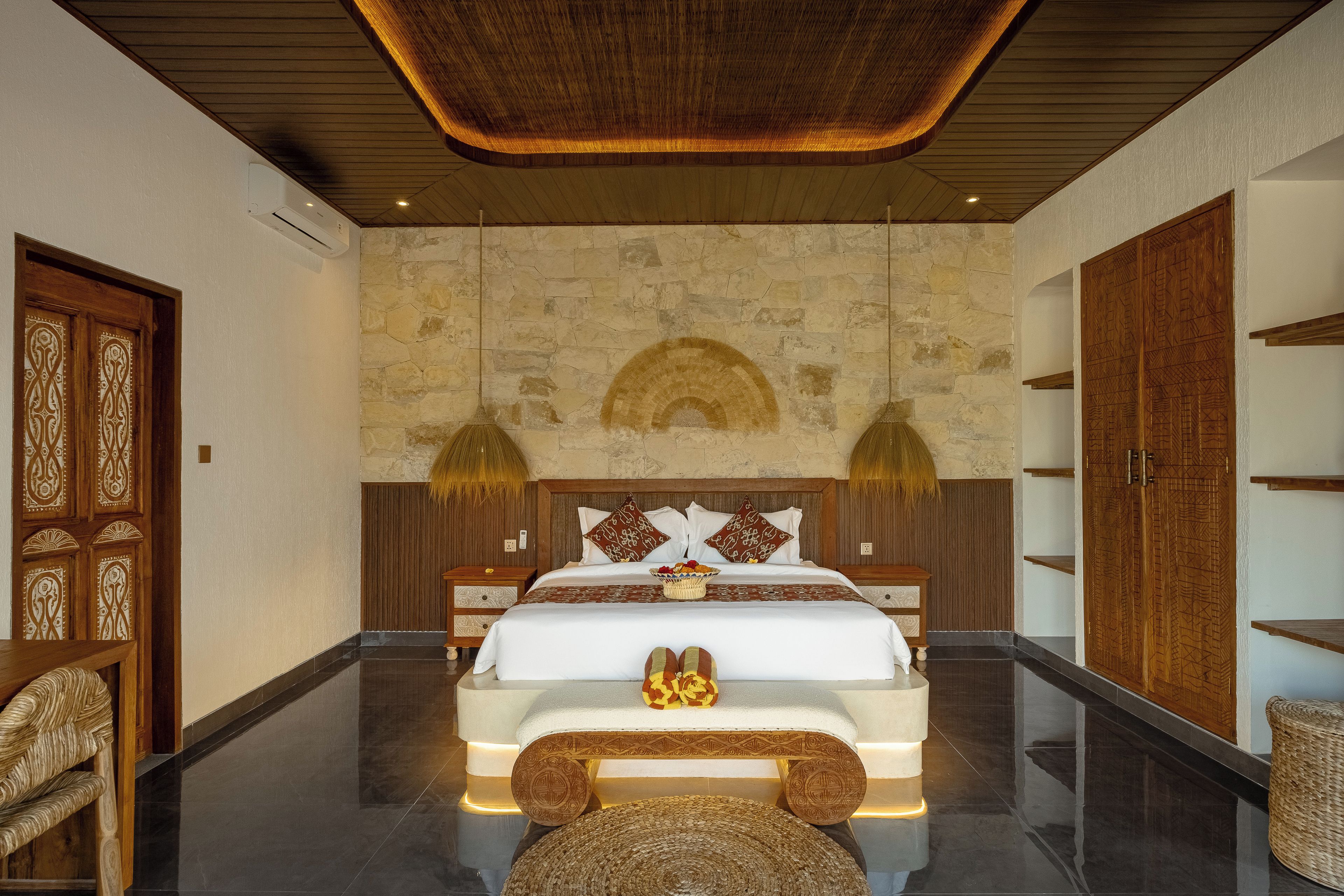 Un dormitorio moderno con una cama grande, una pared de piedra y un techo de madera.